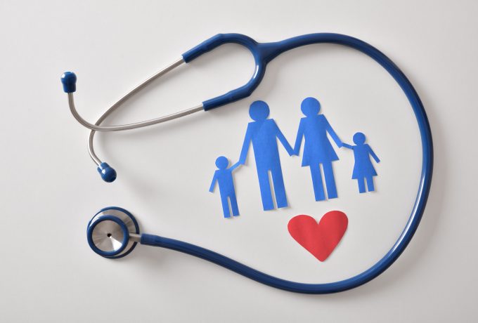 Concept of family medicine with ostetoscope and paper cut Concept of family medicine with ostetoscope and paper cut of family and heart on a white table. Top view. Horizontal composition.